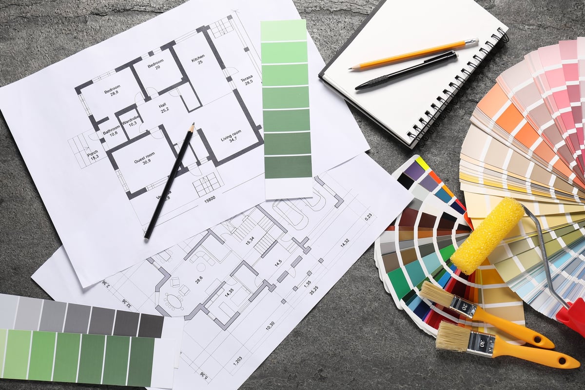 House plans and designer tools laid out on a table, planning a renovation project