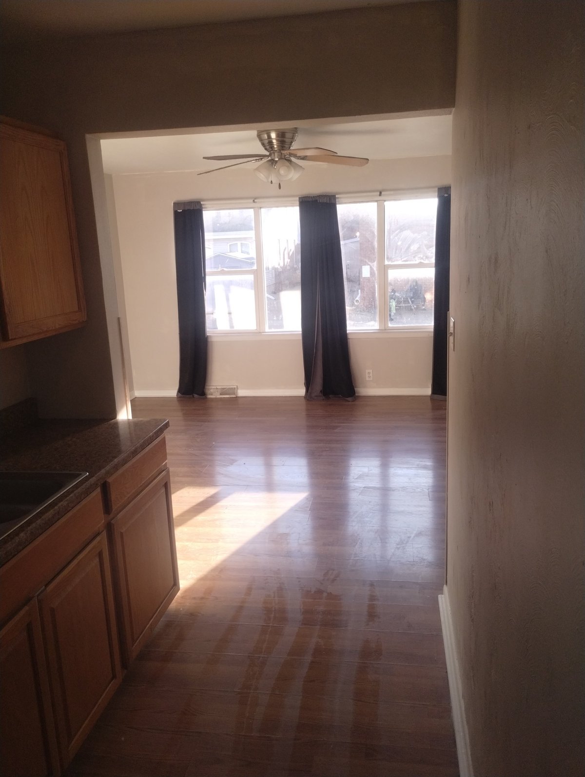 Spacious interior with refinished hardwood flooring, large windows, ceiling fan, and natural light